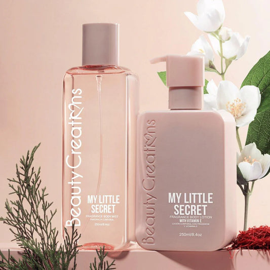 Two bottles of 'My Little Secret' by Beauty Creations on a pink background with flowers and greenery.